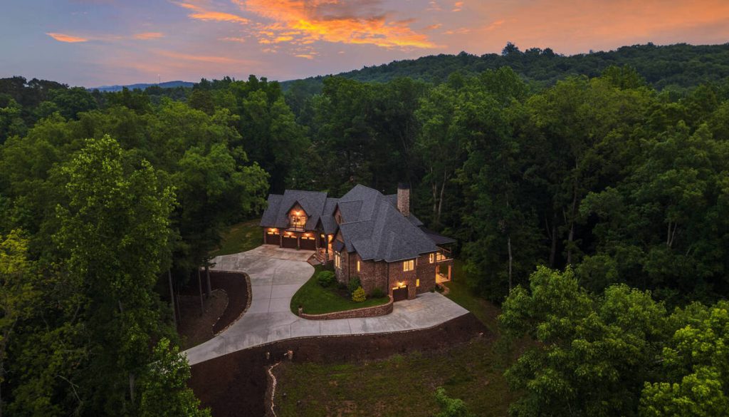 Virtual twilight aerial view of a luxury home surrounded by trees